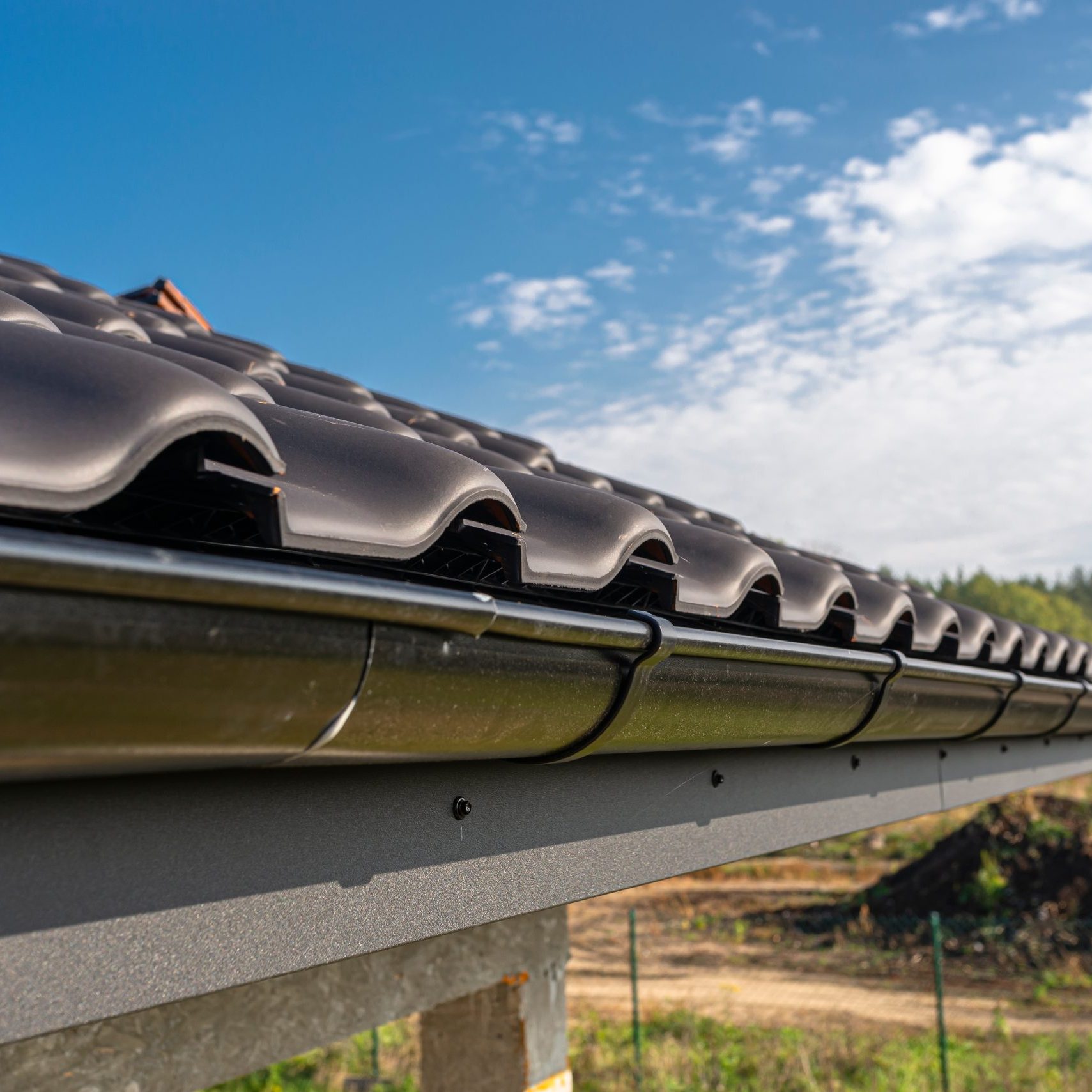 a-metal-black-gutter-on-a-roof-covered-with-ceram-2025-03-12-21-49-17-utc